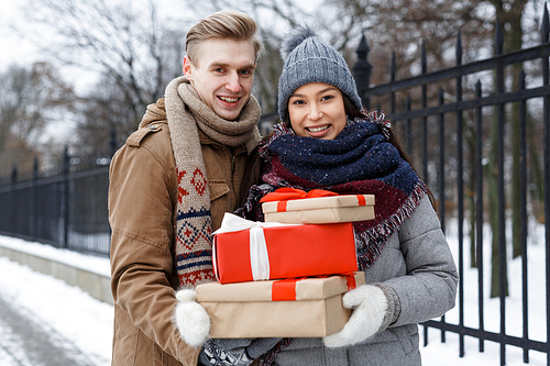 Young couple with xmas presents taking walk on wintery day