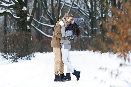 Embracing couple flirting in wintery park at dating