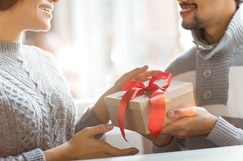Happy young woman taking giftbox with unexpected surprise from her boyfriend hands
