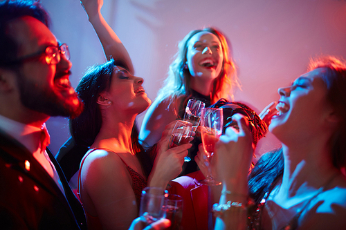 Ecstatic people with flutes of champagne enjoying party