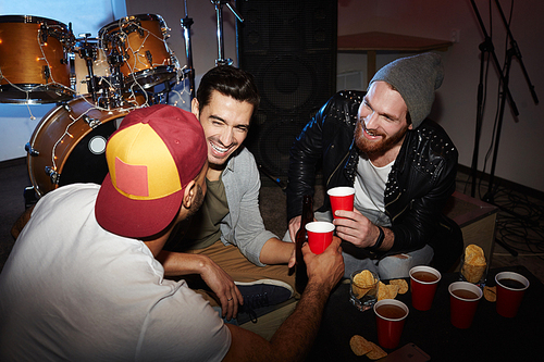 Group of trendy young men hanging out at party in club, drinking beer laughing and having fun