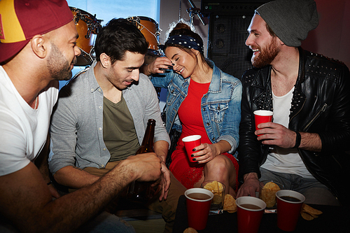 Group of young trendy people chilling in night club, drinking beer and having fun