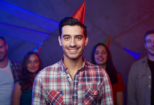 Handsome guy in birthday cap and his friends on background