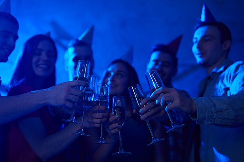 Flutes with champagne held by toasting friends at birthday party