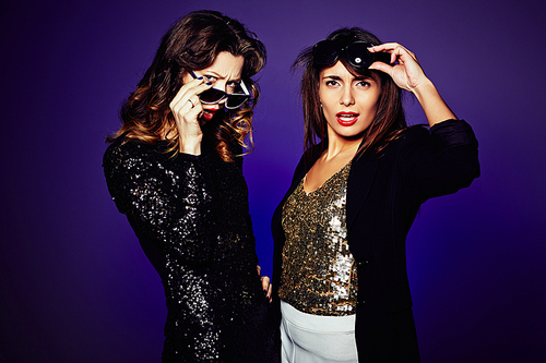 Waist-up portrait of indignant it girls  while standing against dark background