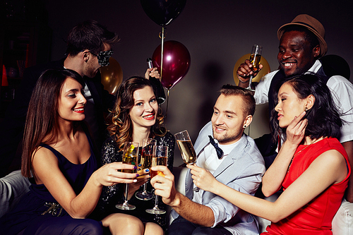 Multi-ethnic group of young people gathered together at home party in order to celebrate birthday of their friend, they toasting with champagne and wishing very best
