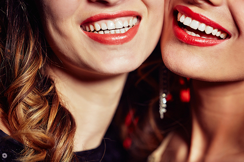 Close-up shot of female dazzling smiles, unrecognizable young women standing cheek to cheek