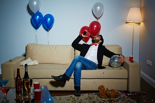 Relaxed man drinking beer from bottle in empty room