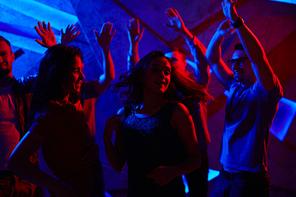 Two girls enjoying dance at disco with guys on background