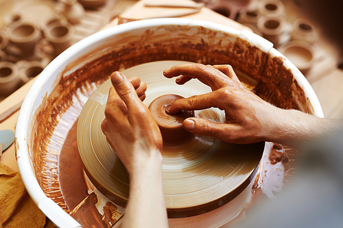 Pottery machine rotating while artisan making jugs
