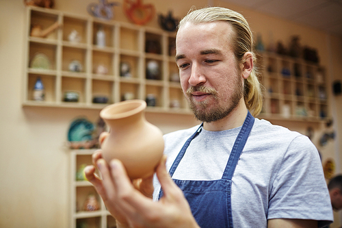 Master of pottery looking at new jug in workshop