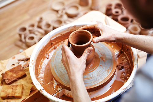 Young master making clay jug in pottery-wheel