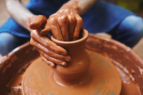 Hands of professional potter making jugs in workshop
