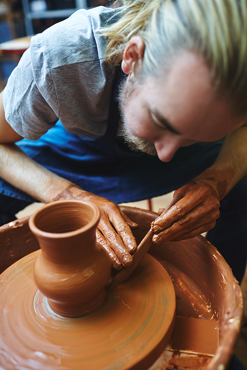 Craftsman finishing up with new jug in pottery wheel