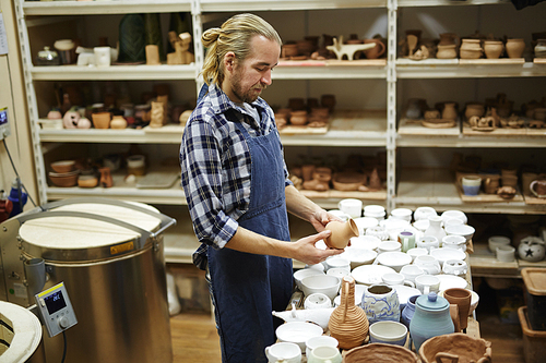 Potter in uniform choosing jug from new collection of earthenware