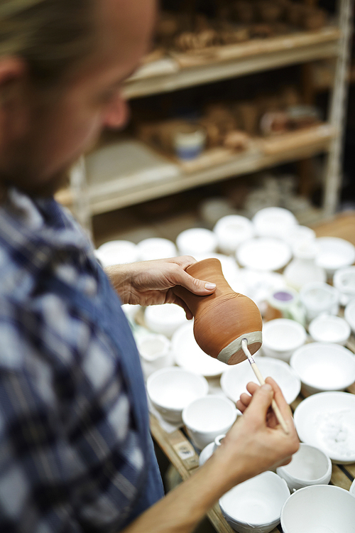 Self-employed craftsman painting his clay jugs