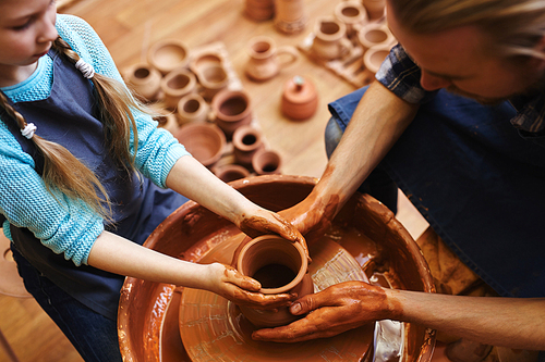 Skilled man and his daughter making clay jugs together