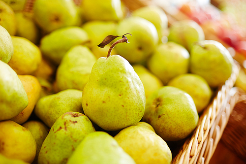 Ripe green juicy pears in basket or special box in supermarket
