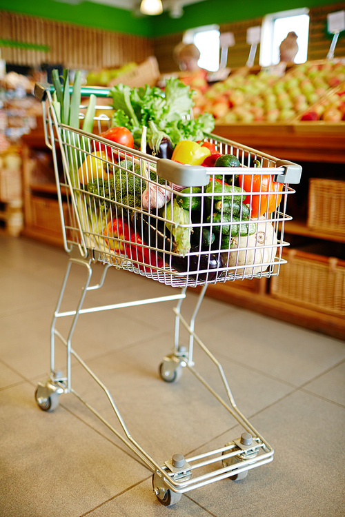 Various colorful vegs and fruits in shopping cart inside supermarket