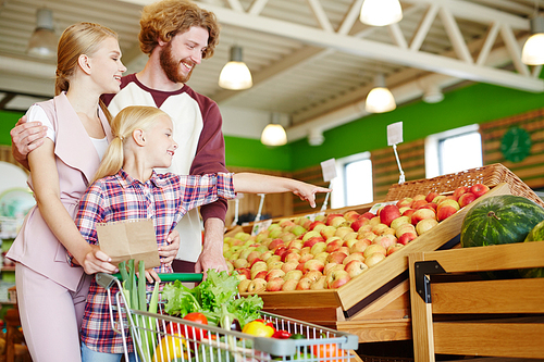 modern family of three choosing water- and other fruits in hypermarket