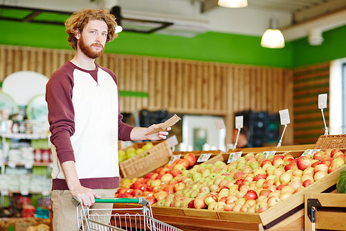 Young customer in casualwear holding shopping list in fruit department