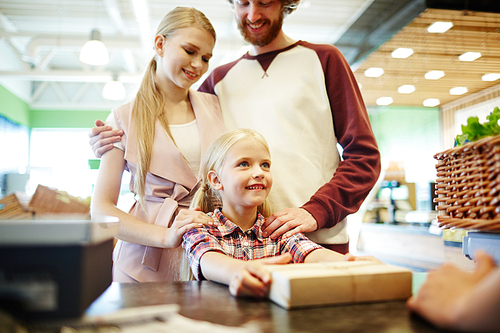 Young family of three buying packed product in supermarket