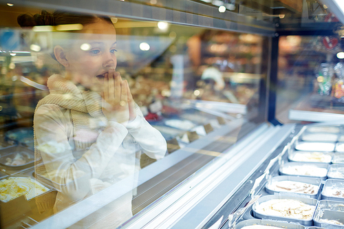 Amazed child looking at showcase with ice-cream assortment