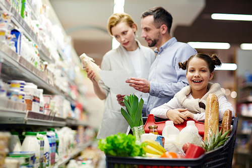 Girl  in supermarket on background of her parents choosing dairy products