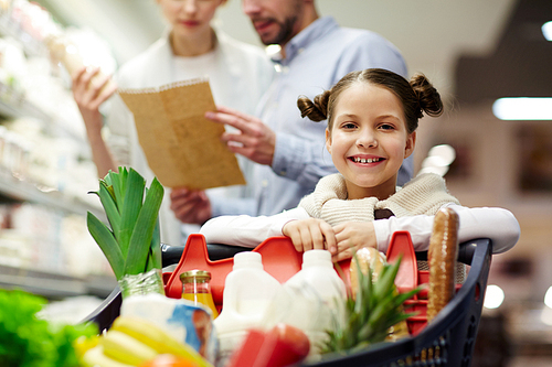 Cute little girl  while her parents choosing food products in supermarket