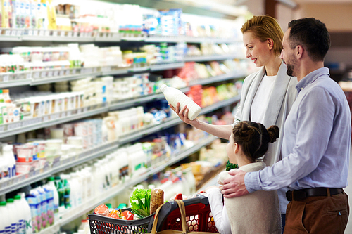 Portrait of happy family shopping in grocery store: buying milk in dairy product department