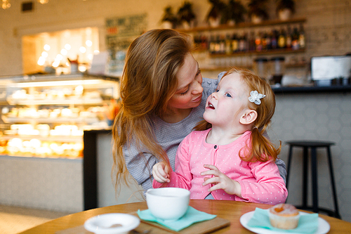 Daughter and mother talking in cafeteria by dessert