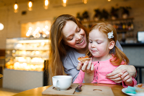Woman offering tasty cupcake to her daughter