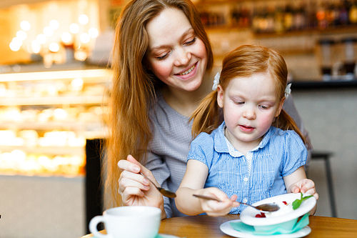 Happy woman and her daughter having dessert in cafe