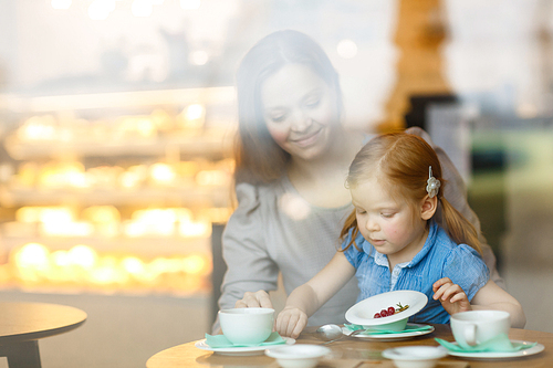 Girl going to eat desert in cafe with her mother near by