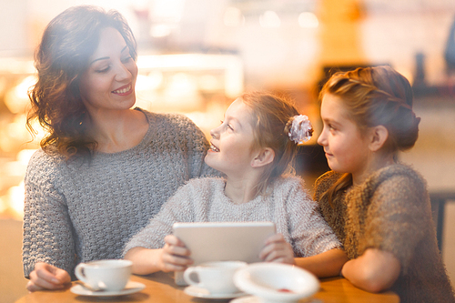Woman and her daughters addicted to gadgets spending time with touchpad in cafe