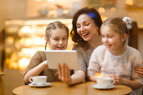 Laughing woman and her daughters looking in touchscreen