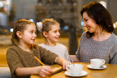 Contemporary woman and her daughters talking in cafe