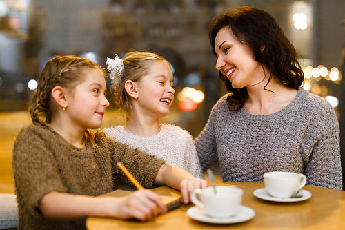 Young woman and her twin daughters spending time in cafe