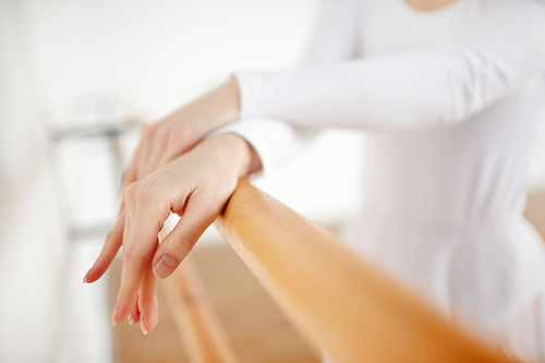 Hands of young ballerina on bar during training before performance