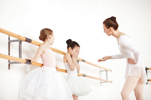 Ballet teacher explaining crying little girl what her problem is after training