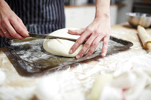 Baker kneading dough and forming loaf of bread