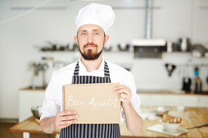 Professional baker holding notepad with wish of good appetite