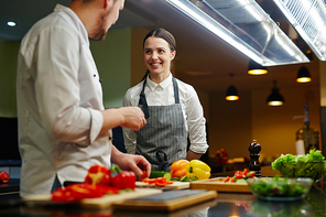 Happy young trainee talking to chef during cooking master class