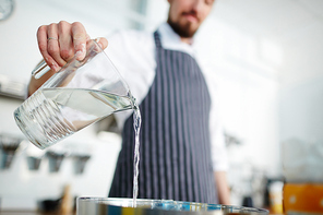 Chef pouring water from jug while cooking