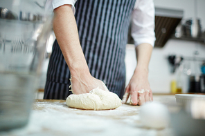 Pastry chef kneading fresh dough for buns