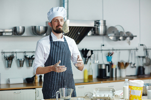 Professional baker throwing dough over table while cooking pastry