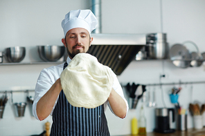 Baker in uniform making flatbread from dough