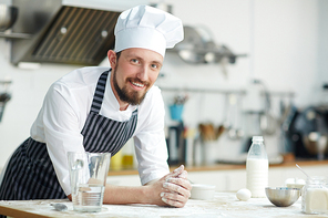 Chef of bakery-shop leaning at workplace