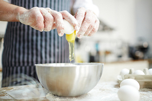 Chef breaking egg into bowl while cooking