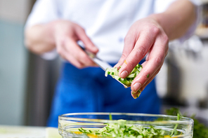 Woman putting cut cucumbers into bowl with salad